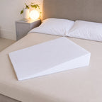 Woman resting upright on a bed wedge with a pillow supporting her head