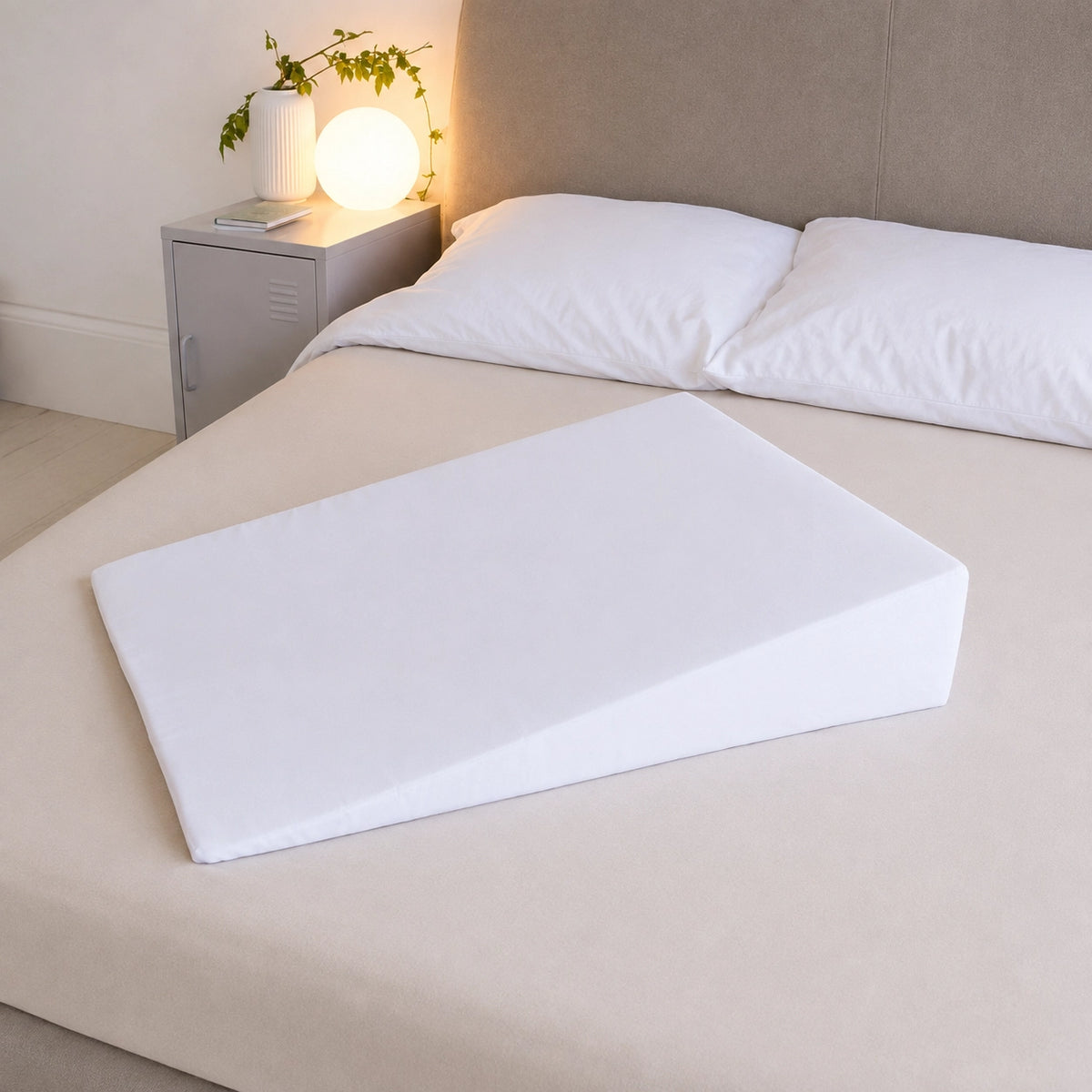 Woman resting upright on a bed wedge with a pillow supporting her head