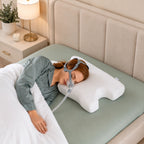 Woman side sleeping in a full-face CPAP mask supported by the Advanced CPAP pillow