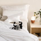 Advanced CPAP pillow on a bed beside a CPAP mask and bedside lamp